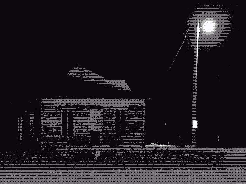 a greyscale, empty house next to a streetlight at night